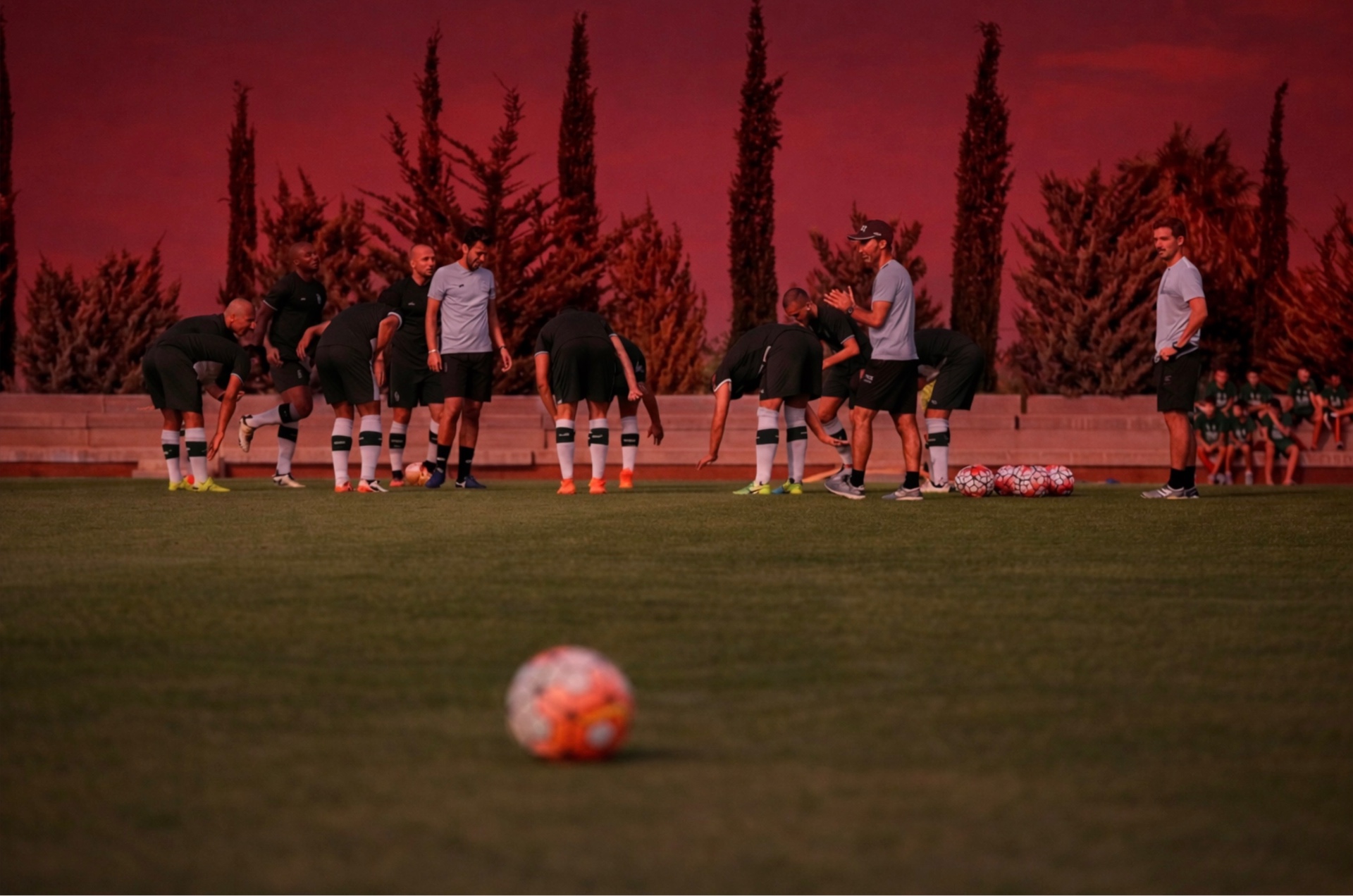 Professional squad stretching on the pitch at sunset during a Lisbon training session
